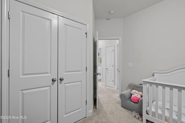 bedroom featuring a nursery area, a closet, and light carpet