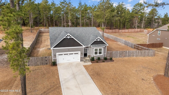 craftsman-style home with stone siding, roof with shingles, fence, and driveway