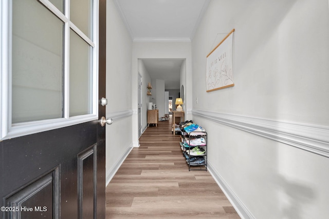 interior space featuring baseboards, light wood-type flooring, and crown molding