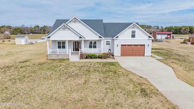 view of front of house with covered porch, a storage unit, an outdoor structure, concrete driveway, and a front lawn