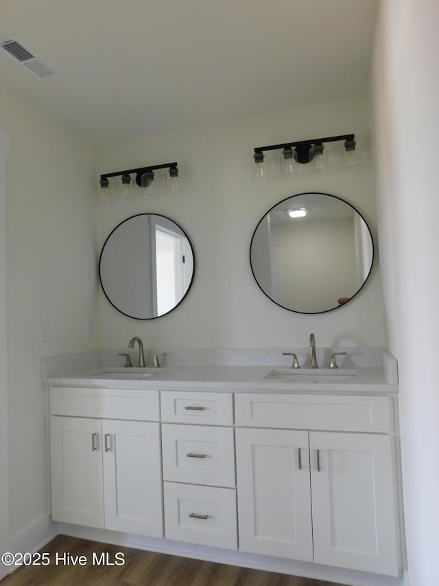 bathroom featuring visible vents, a sink, and double vanity