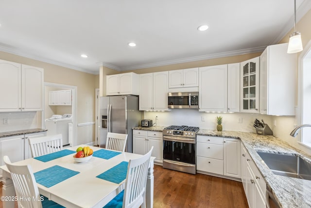 kitchen featuring a sink, dark wood-style floors, washing machine and dryer, stainless steel appliances, and crown molding