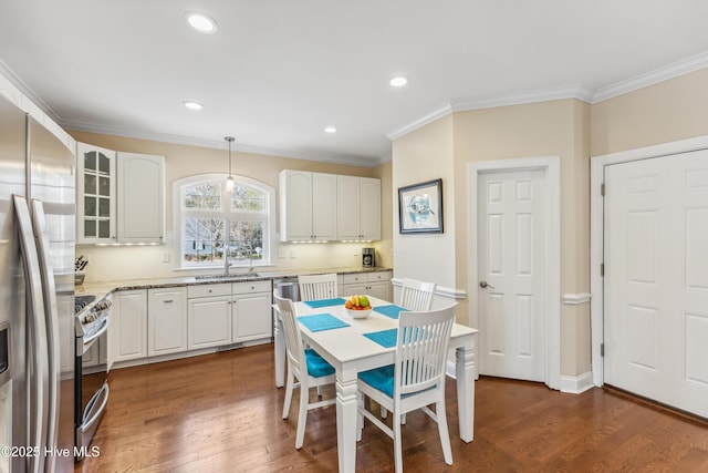 kitchen with dark wood-style floors, a sink, white cabinets, appliances with stainless steel finishes, and crown molding