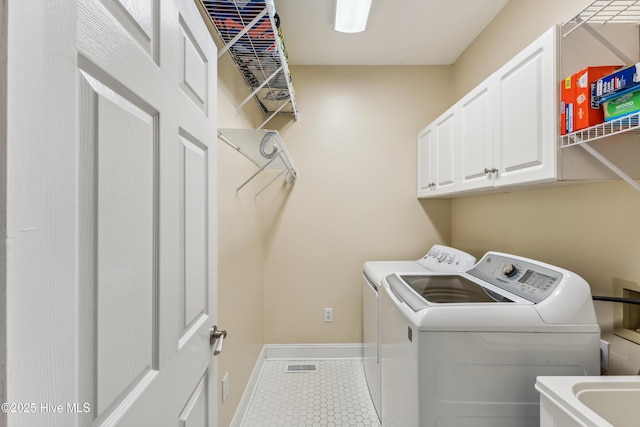 washroom with visible vents, baseboards, tile patterned floors, cabinet space, and separate washer and dryer