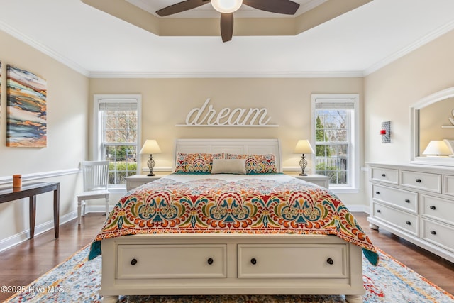 bedroom featuring a tray ceiling, dark wood-style flooring, and ornamental molding