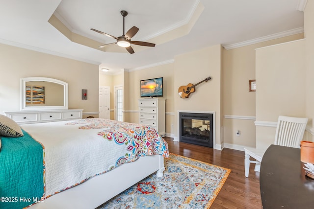 bedroom with wood finished floors, baseboards, a raised ceiling, and ornamental molding