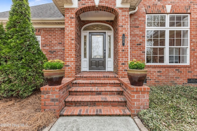 doorway to property featuring brick siding, roof with shingles, and crawl space