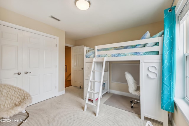 carpeted bedroom with baseboards, visible vents, and a closet