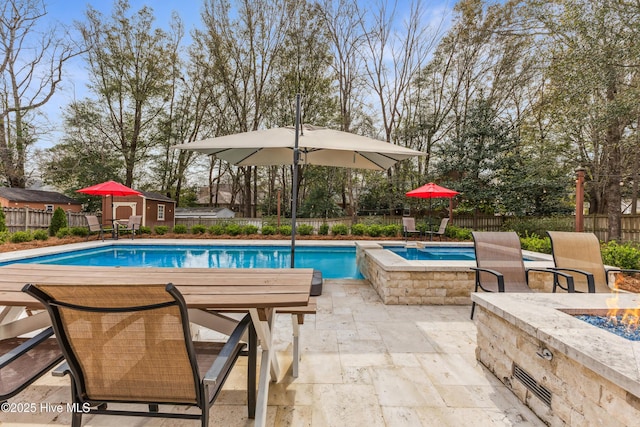 view of swimming pool featuring a fire pit, a pool with connected hot tub, a fenced backyard, and a patio area