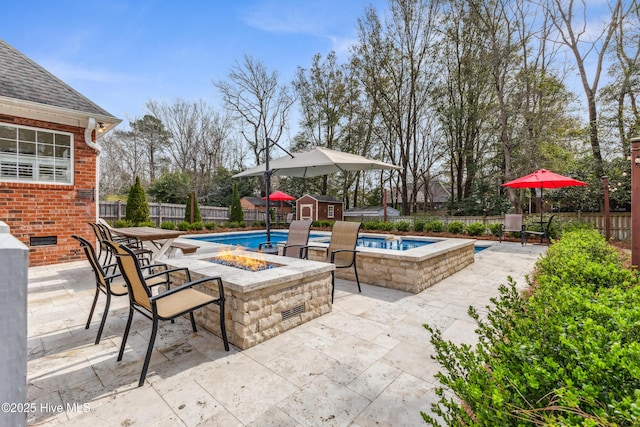 view of patio featuring a fenced in pool, a fire pit, a storage shed, a fenced backyard, and an outbuilding