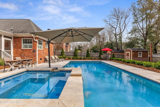 view of swimming pool with a patio, a shed, a fenced backyard, a pool with connected hot tub, and an outdoor structure