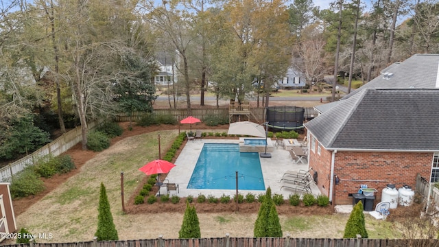 pool featuring a trampoline, a fenced backyard, a lawn, and a patio area