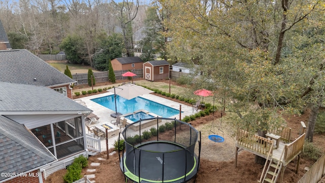 view of pool with a trampoline, a fenced backyard, a shed, an outdoor structure, and a patio area