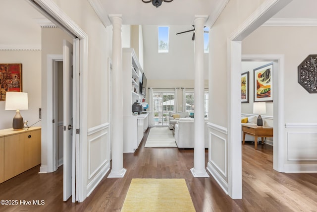 foyer entrance with dark wood finished floors, crown molding, and ornate columns