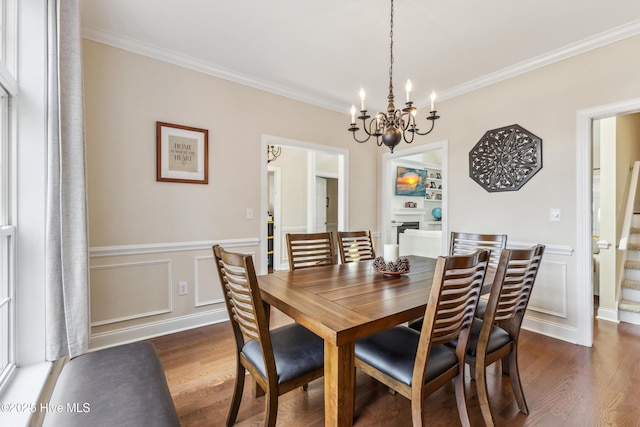 dining room with a chandelier, dark wood-style floors, built in features, and ornamental molding