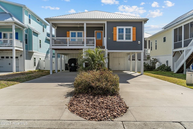 coastal home featuring metal roof, a carport, board and batten siding, and concrete driveway