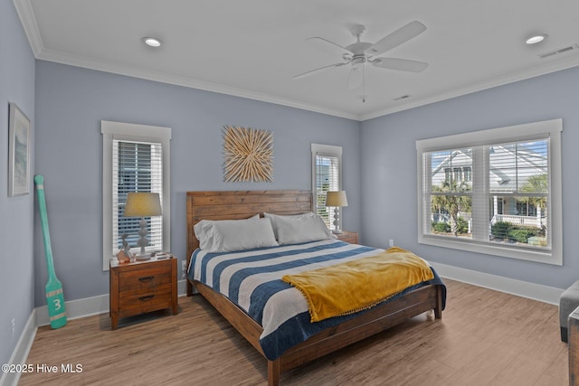 bedroom with ornamental molding, wood finished floors, visible vents, and baseboards