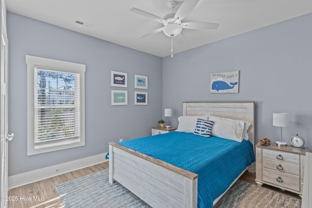 bedroom with ceiling fan, wood finished floors, visible vents, and baseboards