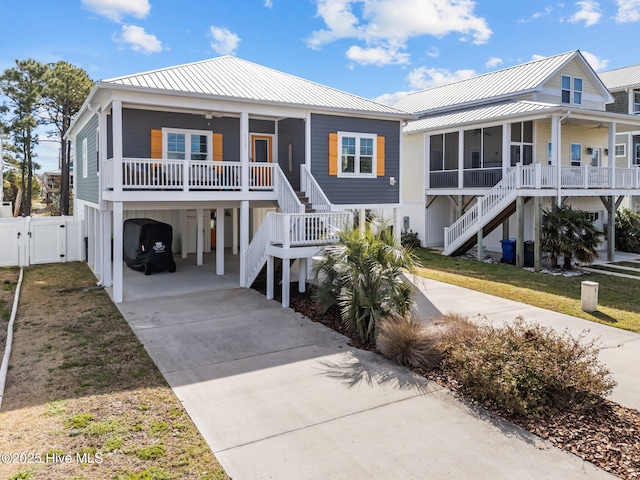 beach home with a sunroom, a gate, driveway, and stairs