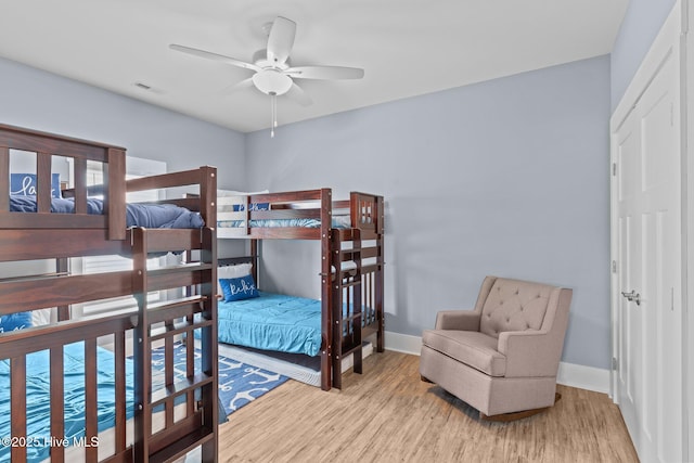 bedroom featuring ceiling fan, wood finished floors, visible vents, and baseboards