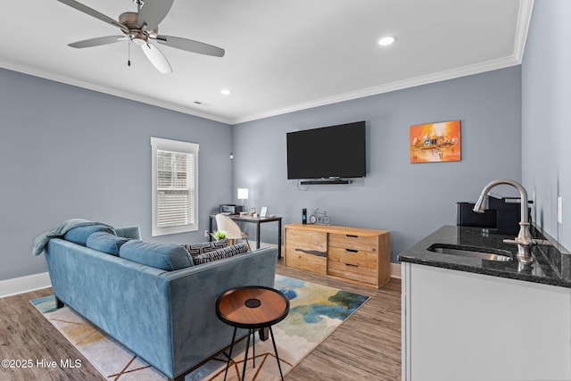 living room with a ceiling fan, light wood-type flooring, crown molding, and baseboards