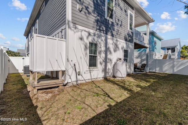 view of side of property with a fenced backyard, cooling unit, and a yard