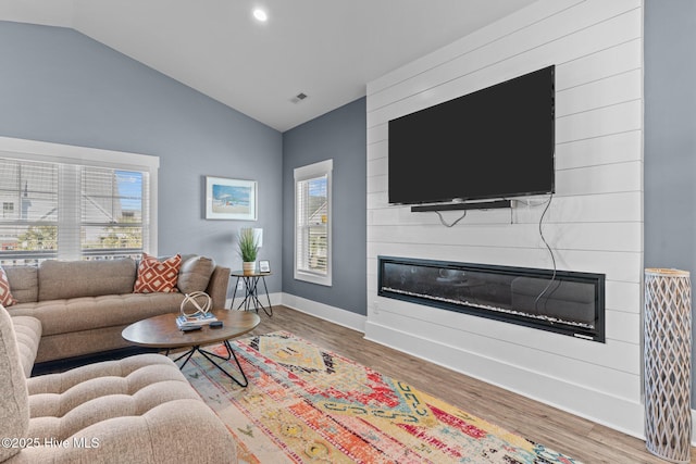 living area with lofted ceiling, a fireplace, wood finished floors, visible vents, and baseboards