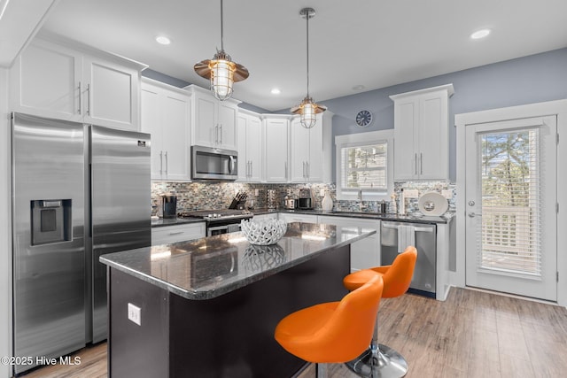 kitchen with light wood-style flooring, stainless steel appliances, backsplash, and a center island