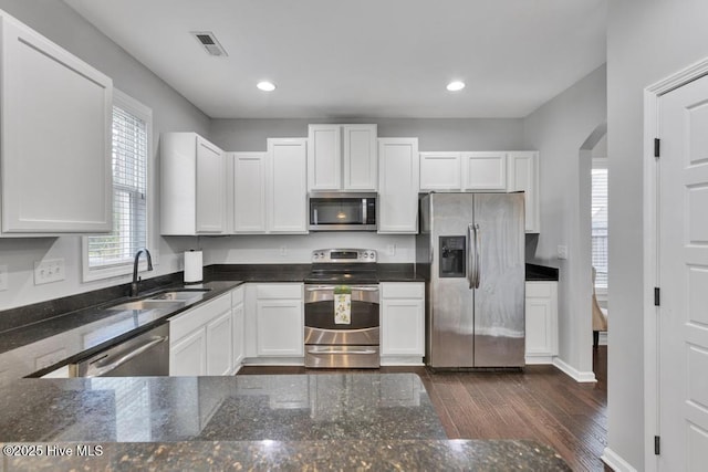 kitchen featuring arched walkways, visible vents, dark wood-style floors, stainless steel appliances, and a sink