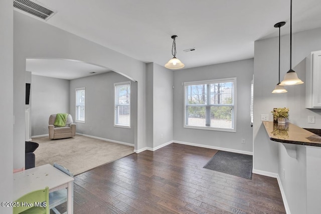 interior space with baseboards, visible vents, arched walkways, and dark wood-style flooring