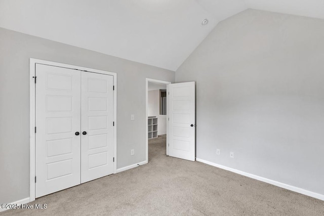 unfurnished bedroom with lofted ceiling, a closet, carpet flooring, and baseboards