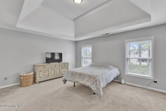 bedroom featuring a tray ceiling, light carpet, visible vents, and baseboards