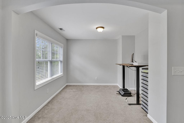 spare room with arched walkways, carpet flooring, visible vents, and baseboards