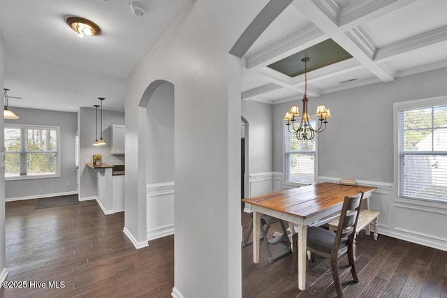 dining space featuring arched walkways, coffered ceiling, wood-type flooring, an inviting chandelier, and beam ceiling