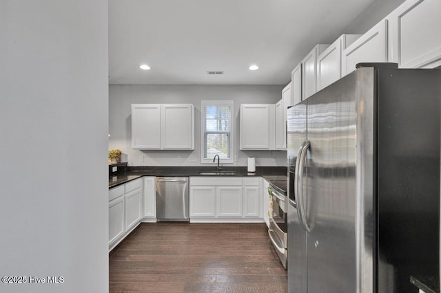 kitchen with visible vents, dark wood finished floors, dark countertops, appliances with stainless steel finishes, and a sink