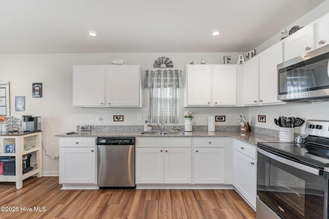 kitchen with appliances with stainless steel finishes, white cabinets, and a sink