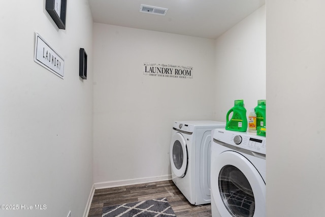 washroom with dark wood-style floors, visible vents, separate washer and dryer, laundry area, and baseboards