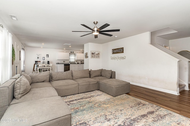 living area featuring baseboards, visible vents, ceiling fan, stairway, and dark wood-style flooring