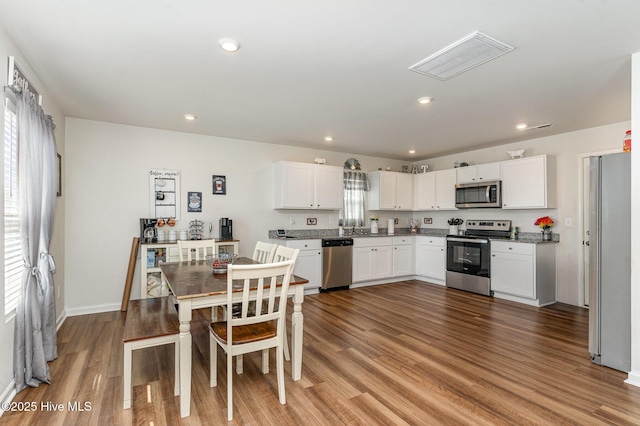 kitchen with stainless steel appliances, wood finished floors, and white cabinetry