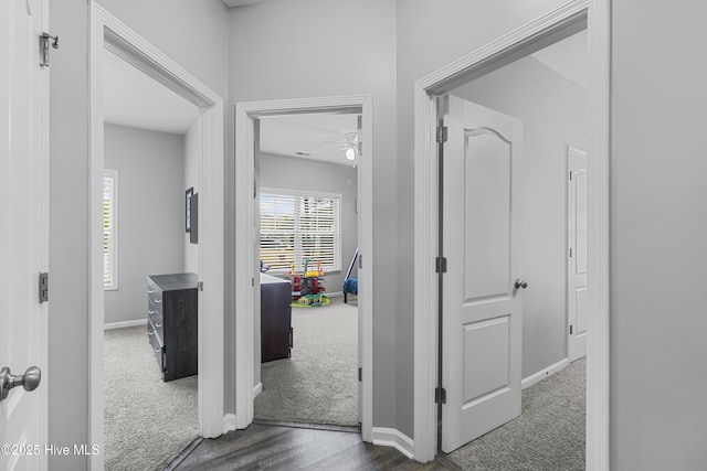 hall with dark carpet and baseboards