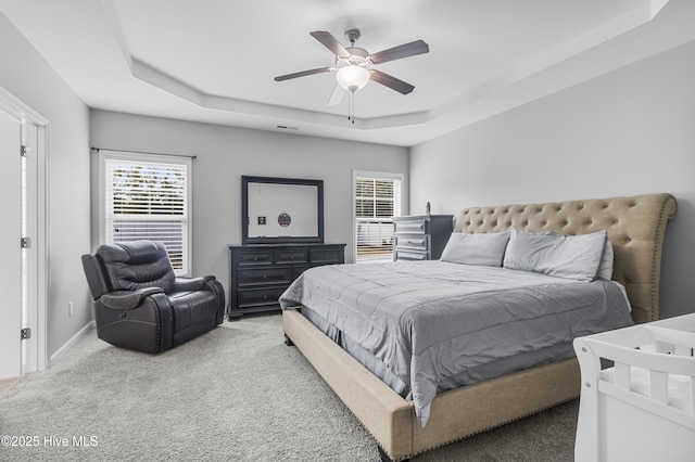 bedroom featuring carpet floors, a tray ceiling, visible vents, and a ceiling fan