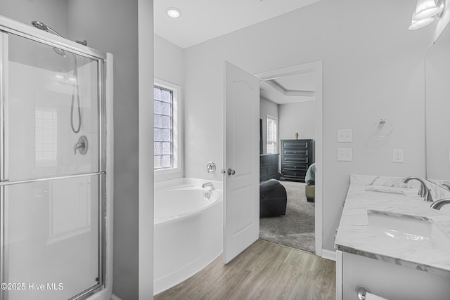 full bathroom featuring a sink, a garden tub, a shower stall, and wood finished floors