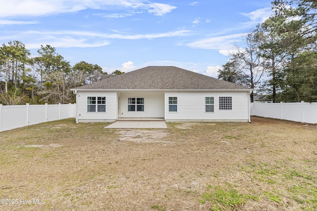 rear view of house with a yard, a fenced backyard, a shingled roof, and a patio