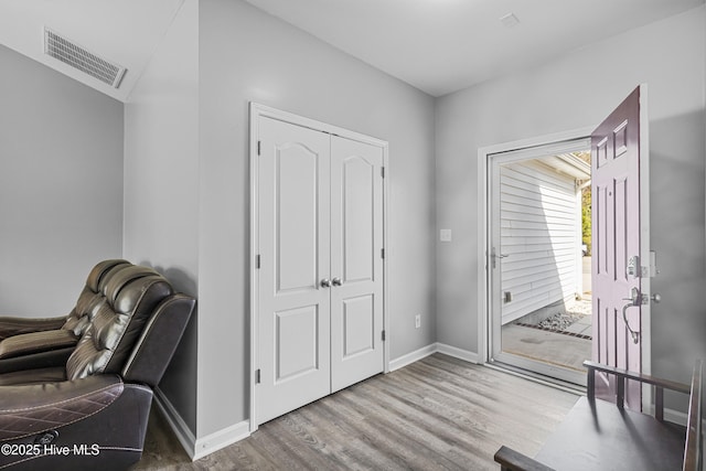 foyer with wood finished floors, visible vents, and baseboards