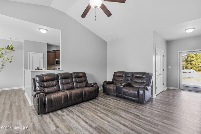 living area featuring vaulted ceiling, light wood-style flooring, and baseboards