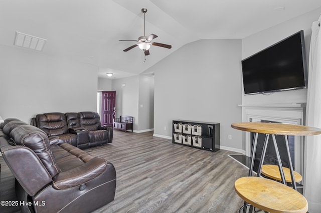 living room featuring lofted ceiling, ceiling fan, wood finished floors, visible vents, and baseboards