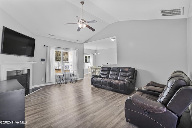 living room with a fireplace with flush hearth, visible vents, vaulted ceiling, and wood finished floors