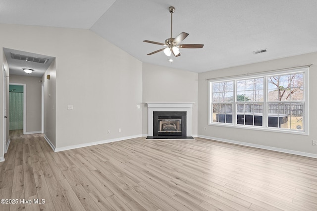 unfurnished living room with a fireplace with flush hearth, vaulted ceiling, visible vents, and light wood-style flooring