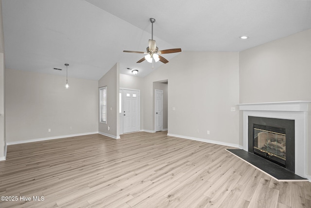 unfurnished living room featuring ceiling fan, baseboards, vaulted ceiling, light wood-style floors, and a glass covered fireplace