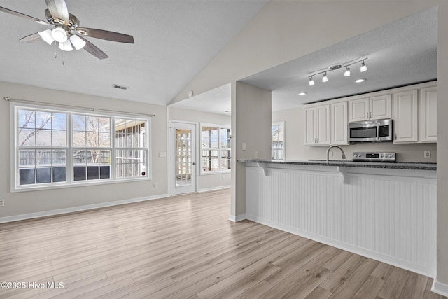 kitchen featuring light wood-type flooring, a breakfast bar area, stainless steel appliances, and a textured ceiling